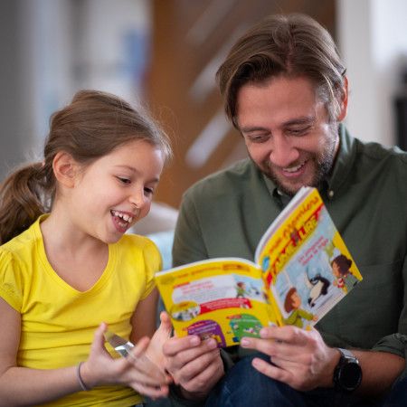 photo d'un père et sa fille en train de lire le magazine Mes premiers j'aime lire